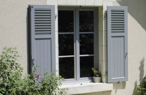 Hellgraue Fensterklappläden an einer Wand mit hellem Putz.