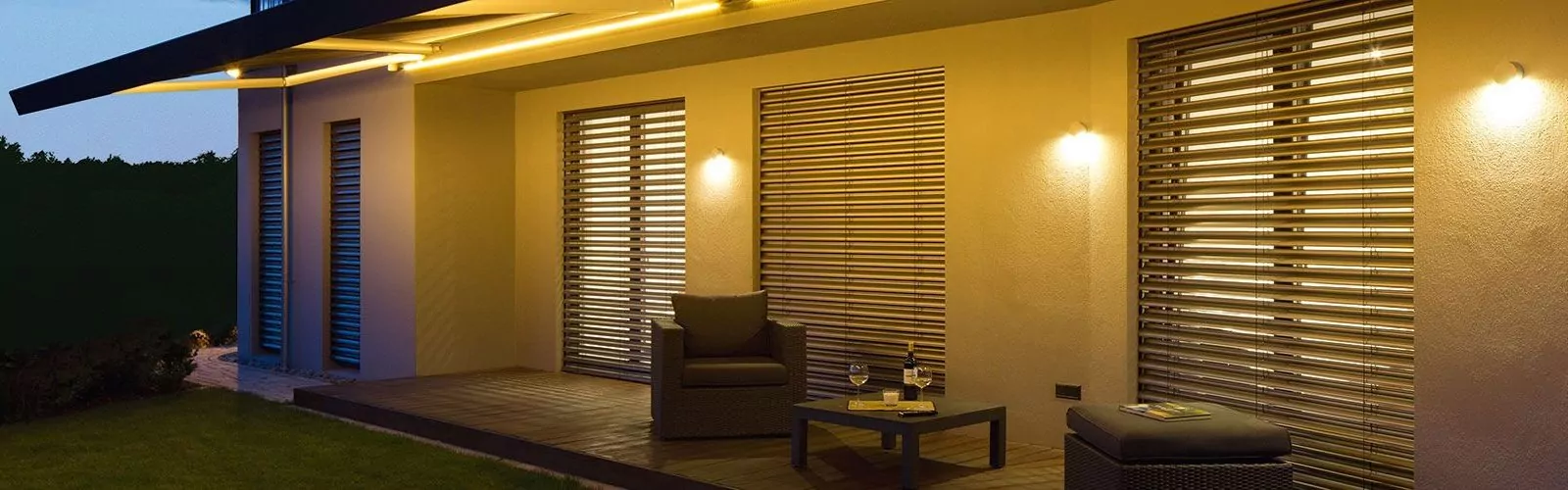 Gebogenes Vordach mit aufliegender Markise über Holzterrasse mit Sitzmöbeln.